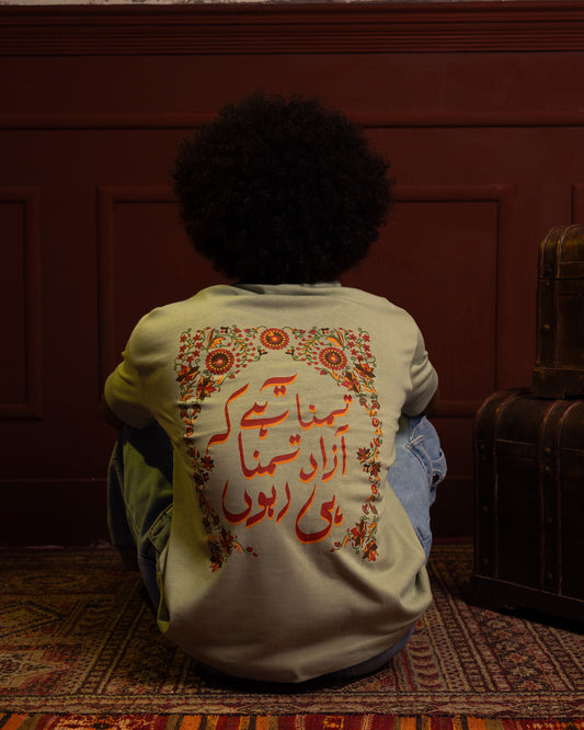 Child sitting on a rug with a patterned shirt in a dimly lit room and wearing oversize t shirt azad